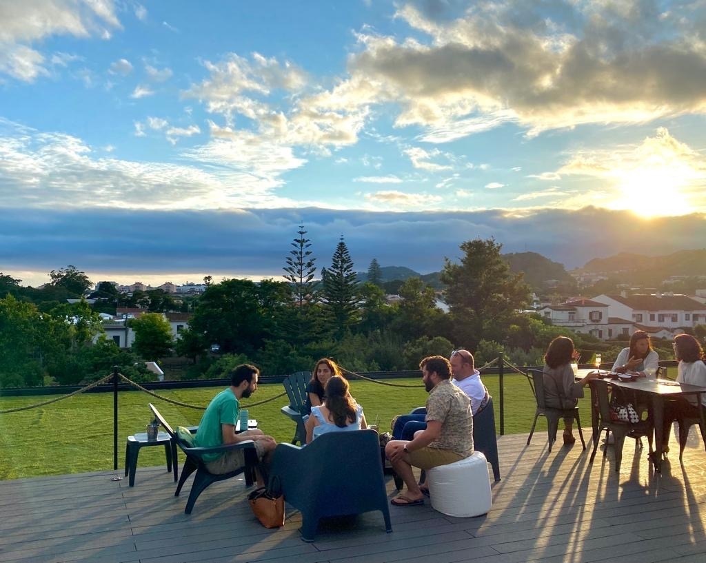 un grupo de personas se sienta alrededor de una mesa en un patio al atardecer