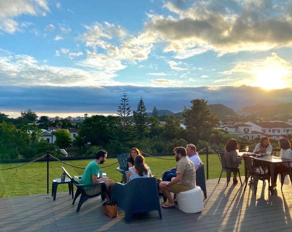 a group of people are sitting on a deck overlooking the ocean