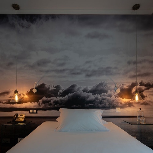 a bedroom with a picture of clouds on the wall