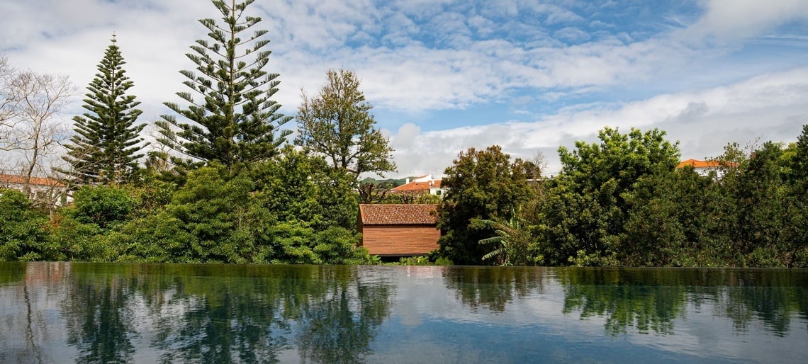 uma pequena cabana de madeira é cercada por árvores ao lado de uma piscina