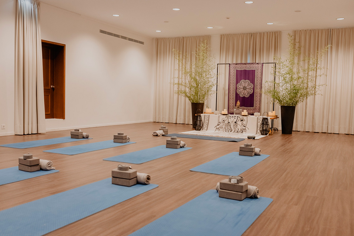 Yoga room at a hotel, featuring blue mats, meditation props, and decor for a peaceful Senhora da Rosa experience.