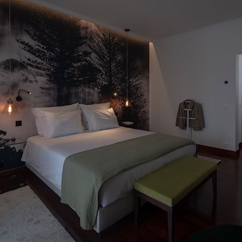 a bedroom with a painting of trees on the wall