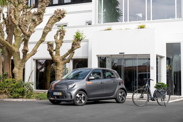 um carro e uma bicicleta estão estacionados em frente a um prédio