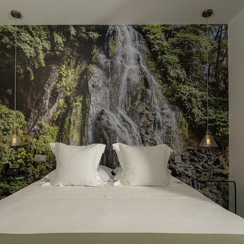 a bedroom with a picture of a waterfall on the wall