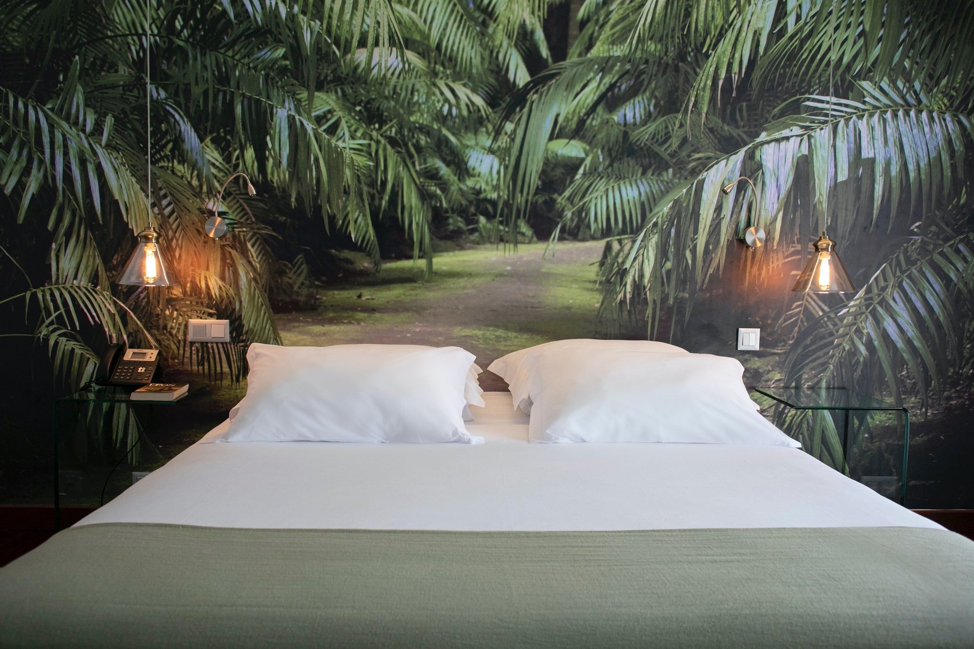 a bed with a picture of a jungle on the wall behind it