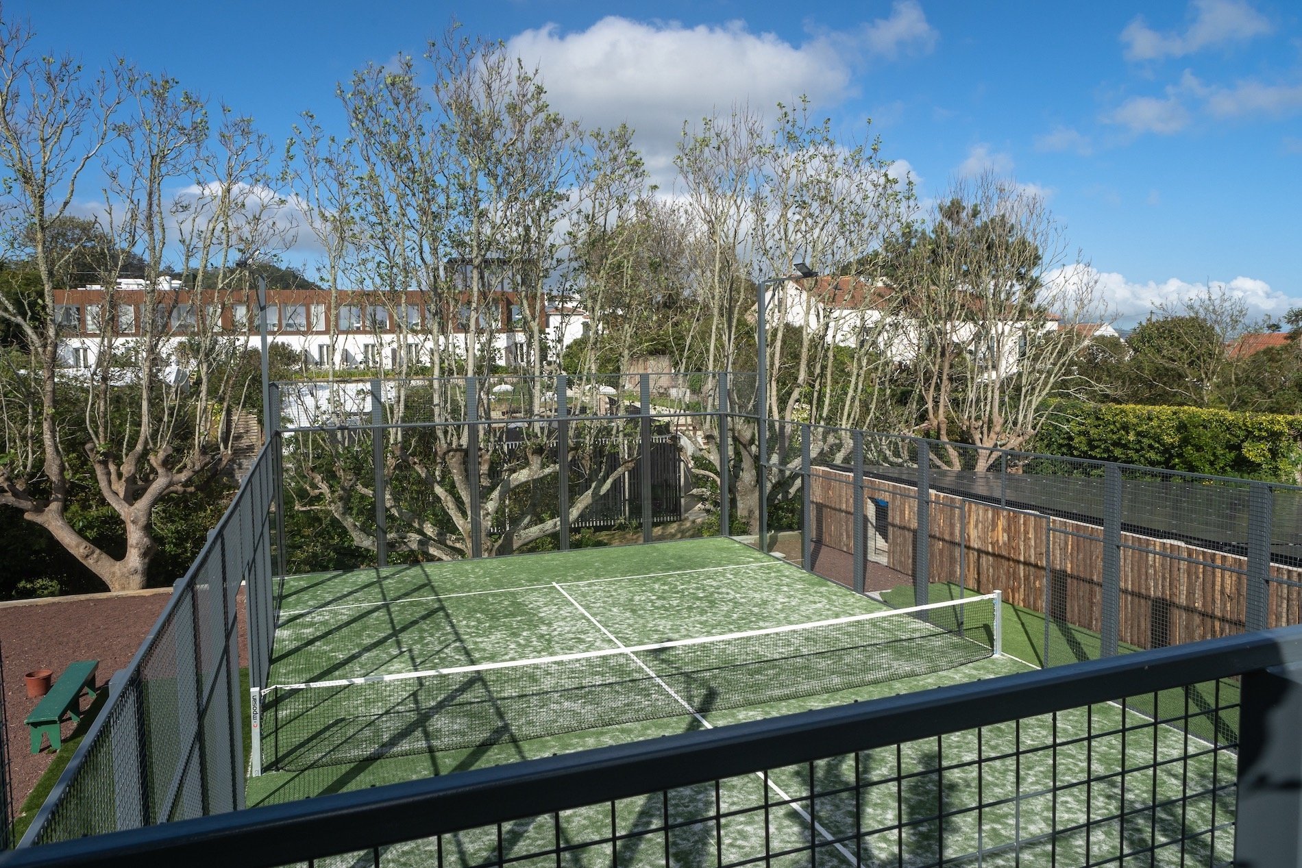 una cancha de tenis con una red y árboles en el fondo