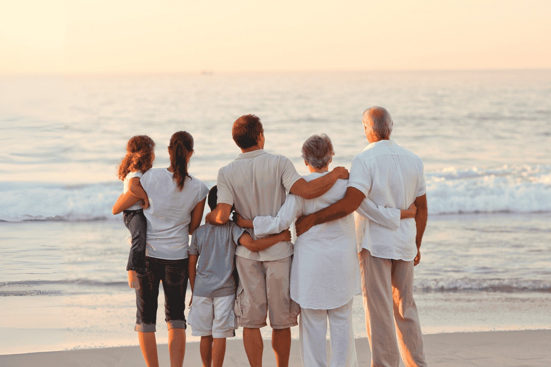 una famiglia è in piedi sulla spiaggia e guarda l' oceano