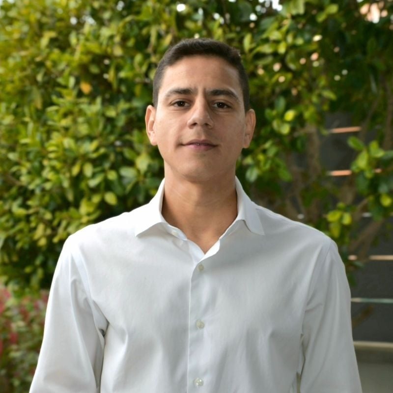  eine Frau in einem weißen Hemd steht mit ihren Armen verschränkt und lächelt 