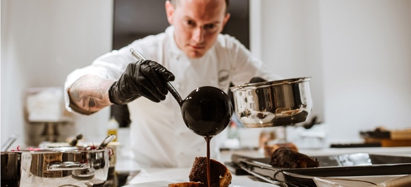 un chef verse de la sauce au chocolat sur un morceau de viande