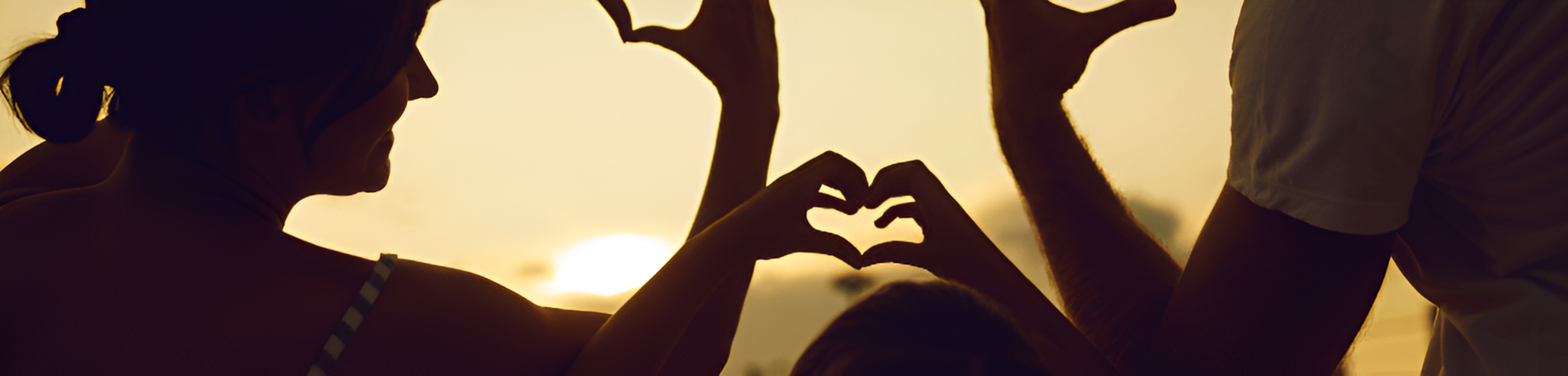 una famiglia fa un cuore con le mani al tramonto