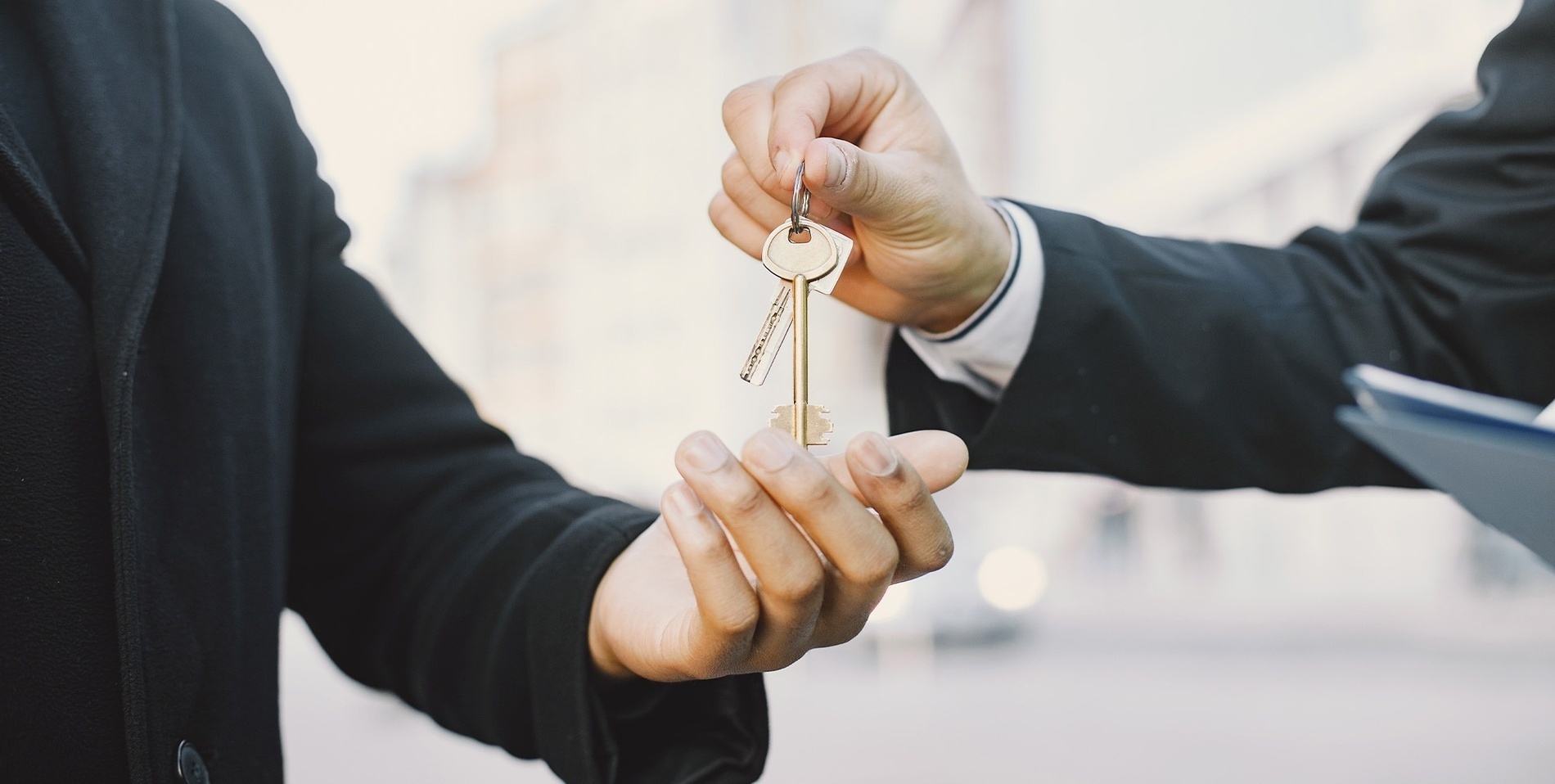 a man in a suit is handing a key to another man