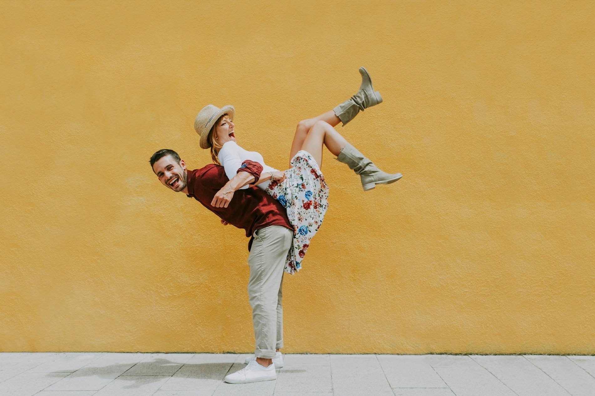 un uomo tiene in braccio una donna in piedi davanti a un muro giallo