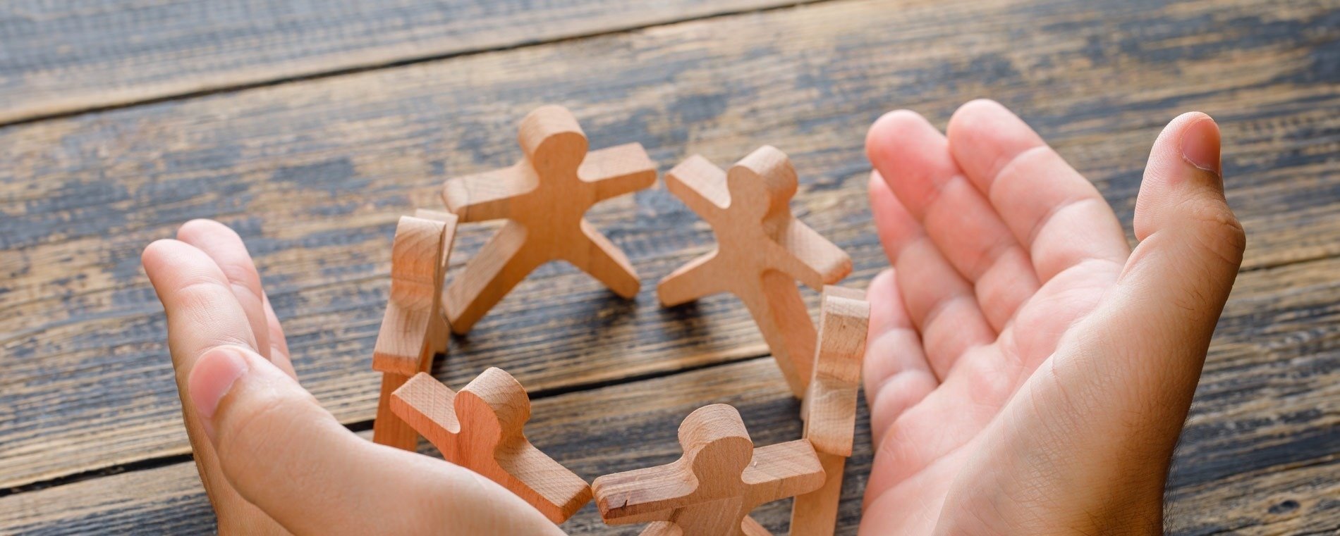 a person holding a circle of wooden people in their hands