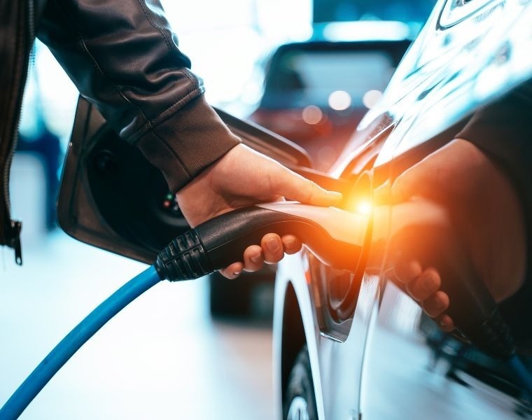 eine Person lädt ein Elektroauto mit einer Ladestation