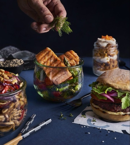 une personne ajoute de l' aneth à un bol de saumon et de brocoli