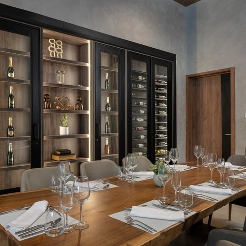 a long wooden table with wine glasses and silverware on it