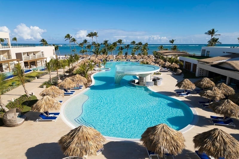 une grande piscine entourée d' ombrelles et de chaises longues avec l' océan en arrière-plan