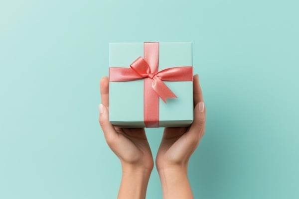 a woman is holding a gift box with a pink bow
