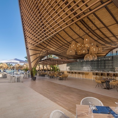 a restaurant with tables and chairs under a wooden roof