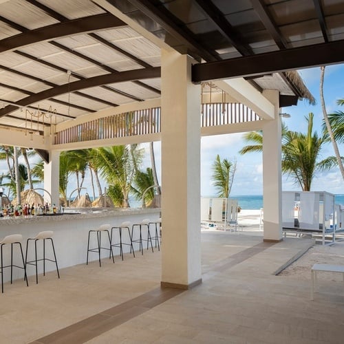 a bar with a view of the ocean and palm trees