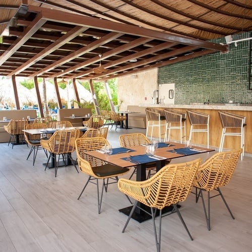 a restaurant with tables and chairs under a thatched roof