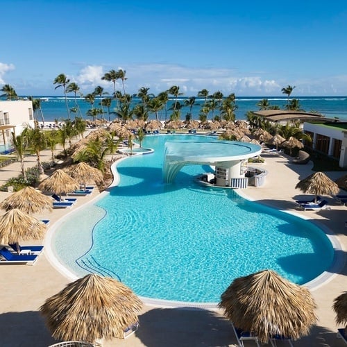 une grande piscine entourée d' ombrelles et de chaises longues avec l' océan en arrière-plan