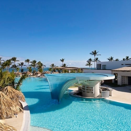 una gran piscina rodeada de sombrillas y sillas en un resort