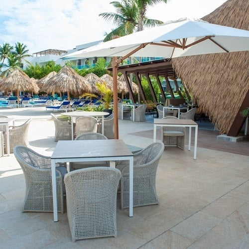 eine Terrasse mit Tisch und Stühlen und einem großen weißen Regenschirm