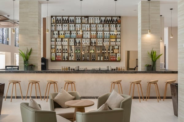 a bar with stools and chairs in front of a wall of liquor bottles