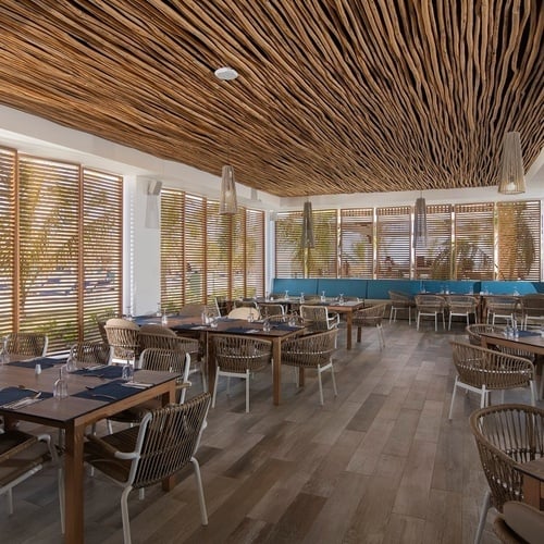 une salle à manger avec des tables et des chaises et un plafond en bois