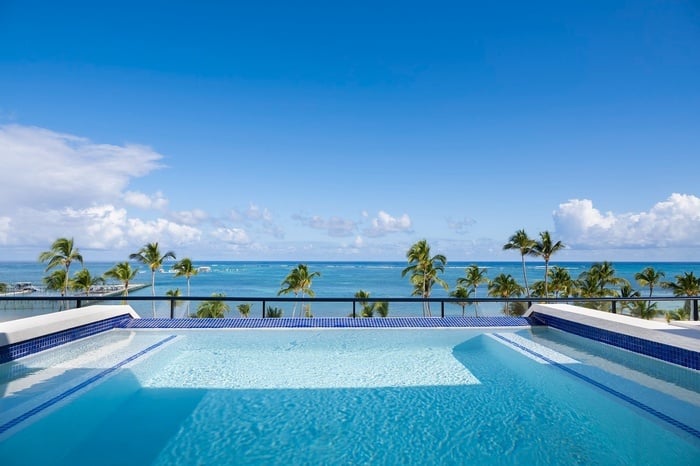 a swimming pool with a view of the ocean and palm trees
