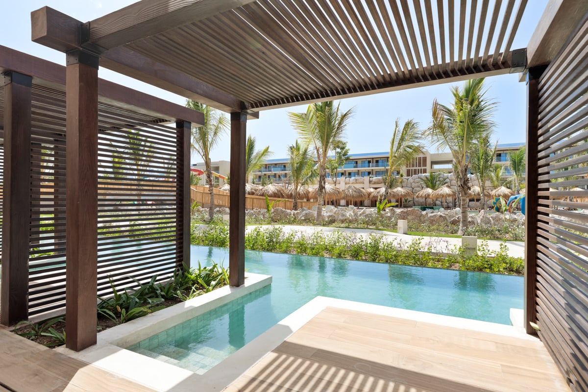 Luxe swim-up hotelkamer met privé terras en zwembad, omgeven door palmbomen en modern resort.