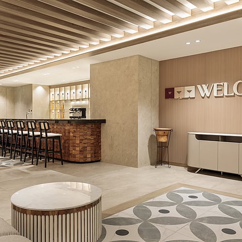 Hotel lobby with bar, seating, and Serenade Caribe Club welcome sign.