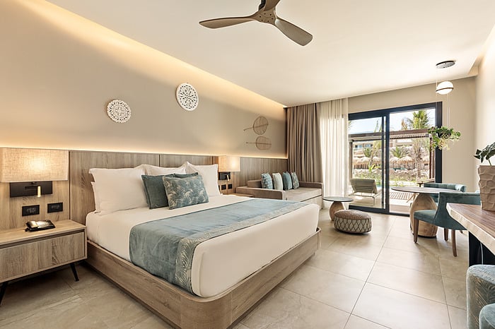 Suite moderne au Serenade Caribe Club avec lit King, canapé et art mural.