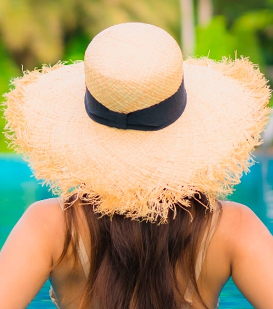 una mujer con un vestido blanco se para frente a una palmera