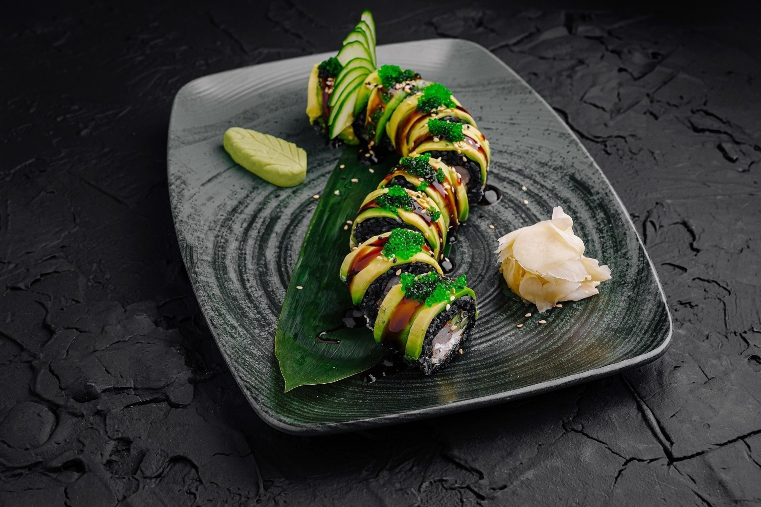 a black plate with a sushi roll on it