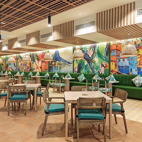 Tropical dining at a vibrant hotel restaurant with colorful murals and comfortable seating. Serenade Caribe Club