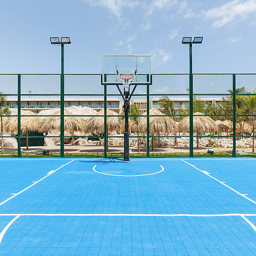 Blue basketball court at resort with palm trees and thatched roofs Serenade Caribe Club