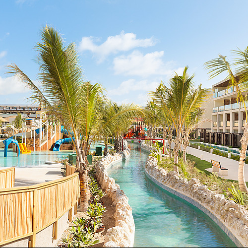 Río lento y toboganes enSerenade Corpo: resort con palmeras y piscina.