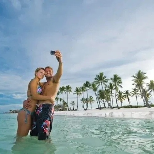 un hombre y una mujer están tomando un selfie en la playa .