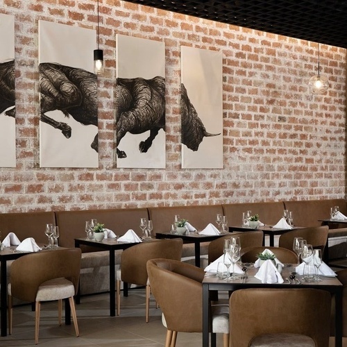 un restaurante con mesas y sillas y cuadros de toros en la pared