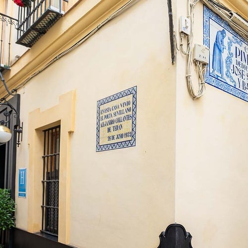 Encantadora fachada de hotel en Sevilla, con balcones, plantas y azulejos históricos de Calle Pimienta.