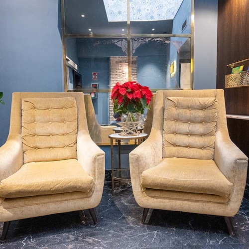 Acogedor lobby de hotel con dos cómodos sillones, mesa central con flor de pascua y decoración moderna.
