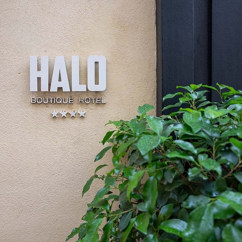 Exterior Halo Boutique Hotel: letrero 4 estrellas en pared beige con hojas verdes. Entrada atractiva.