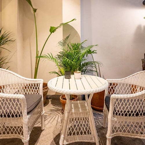 Terraza de hotel acogedora con muebles de mimbre y plantas, ideal para relajarse.