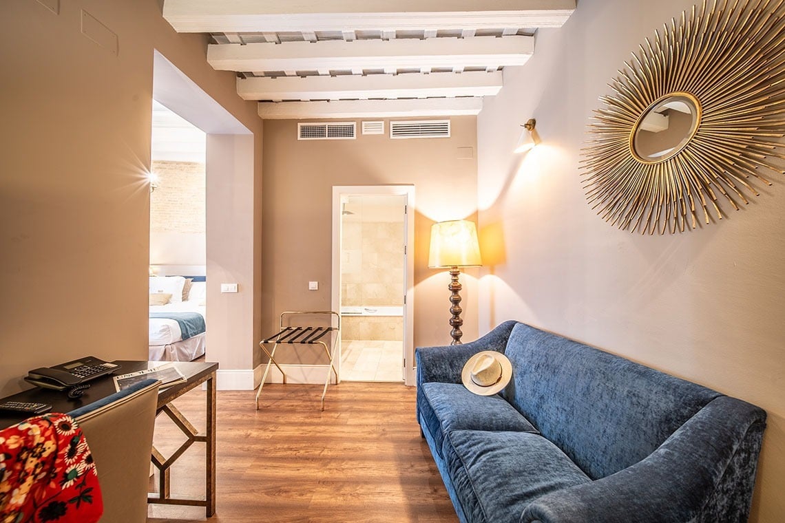 Sofá azul junto a lámpara y espejo sol en habitación de hotel SHC: Halo Boutique Hotel.