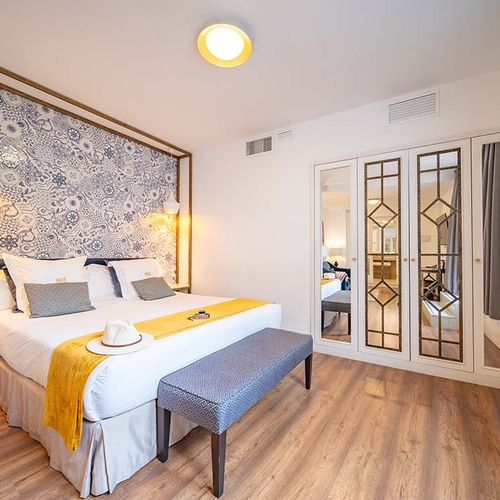 Habitación de hotel moderna: cama king, pared con patrón azul y blanco, armario con espejos, suelo madera.