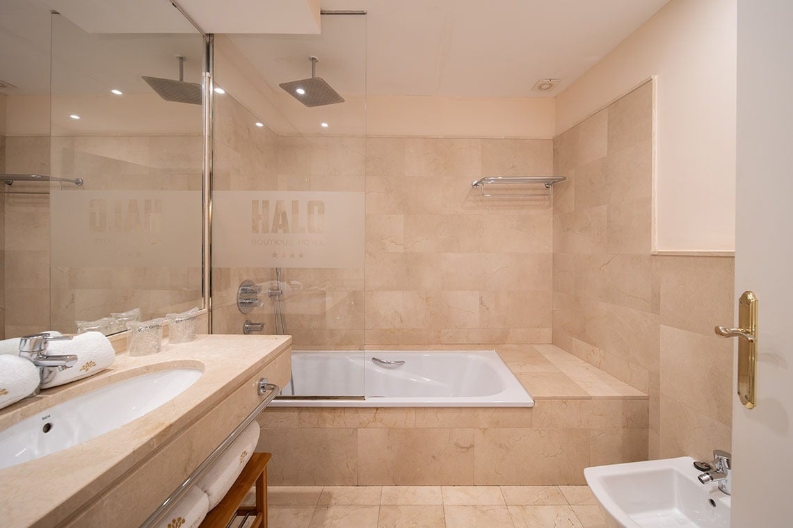 Baño elegante en SHC: Halo Boutique Hotel con bañera, lavabo y ducha.