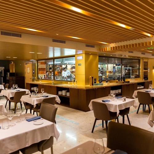 a restaurant with tables and chairs and a chef in the kitchen