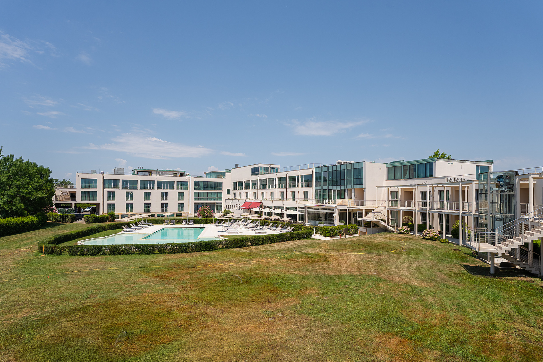Hotel Pisa Plaza 5* | Official Website: Modern facade with a flowered garden and historical boat.